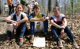 three orienteers, seated on the ground after their race